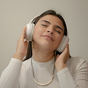 A woman enjoying music with headphones, eyes closed, expressing relaxation and peace—a reminder of the soothing power of self-care and mindfulness.