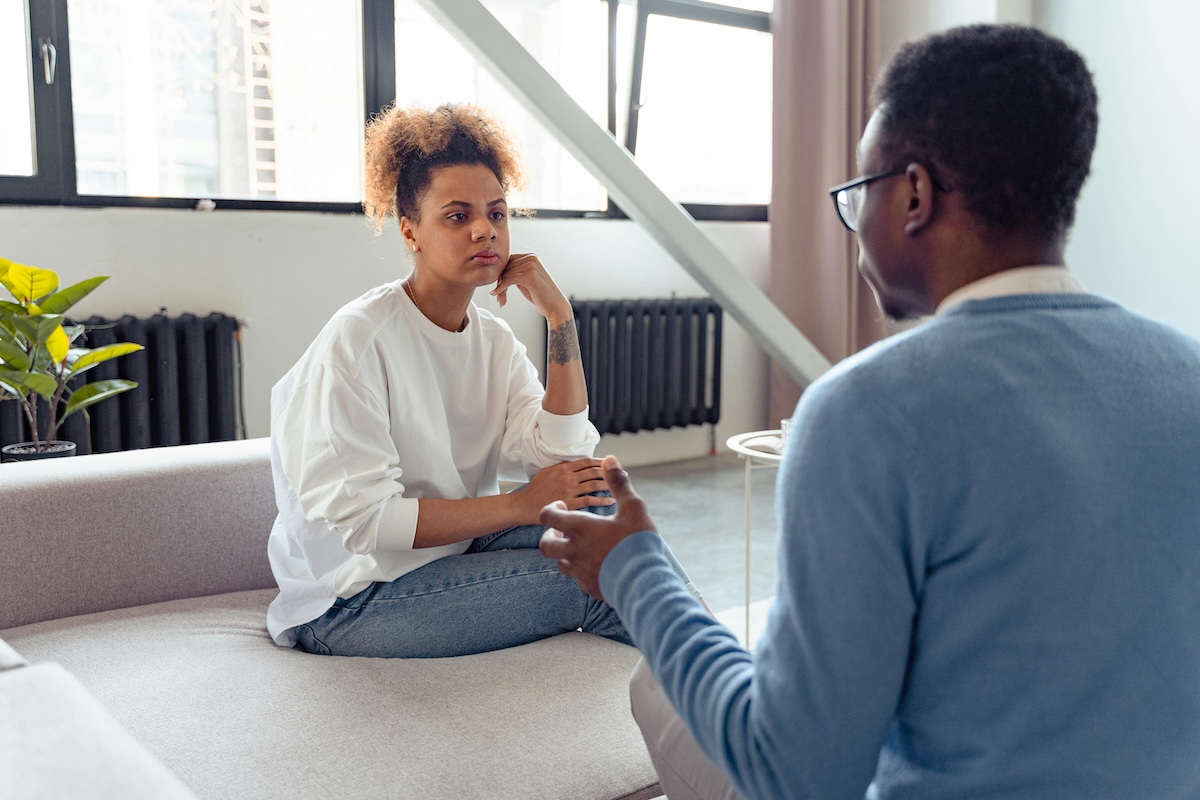 A couple sits together during a difficult but respectful conversation, practicing the skills needed to address controlling behaviors and work through their underlying causes.