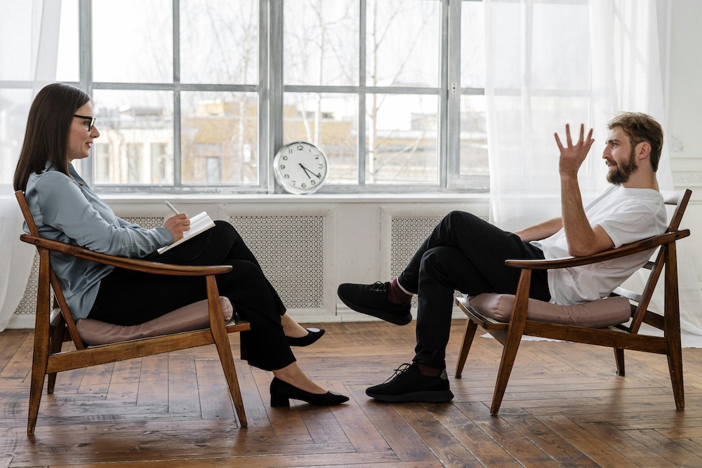 A man in a counseling session, talking to a therapist in a compassionate, confidential, and professional setting, highlighting the role of counseling in porn addiction recovery.