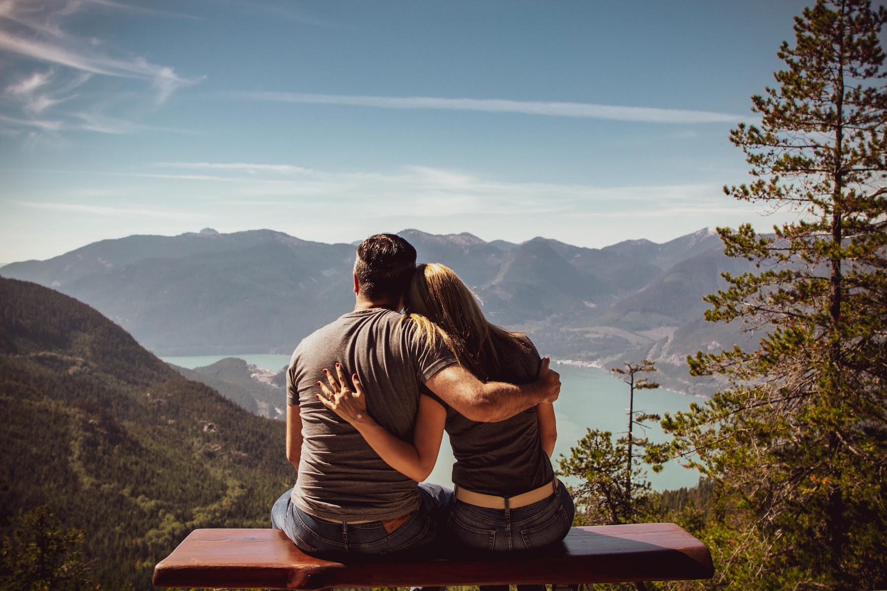 A couple sits on a park bench overlooking a serene lake and mountains, symbolizing peace and connection during pornography addiction recovery.