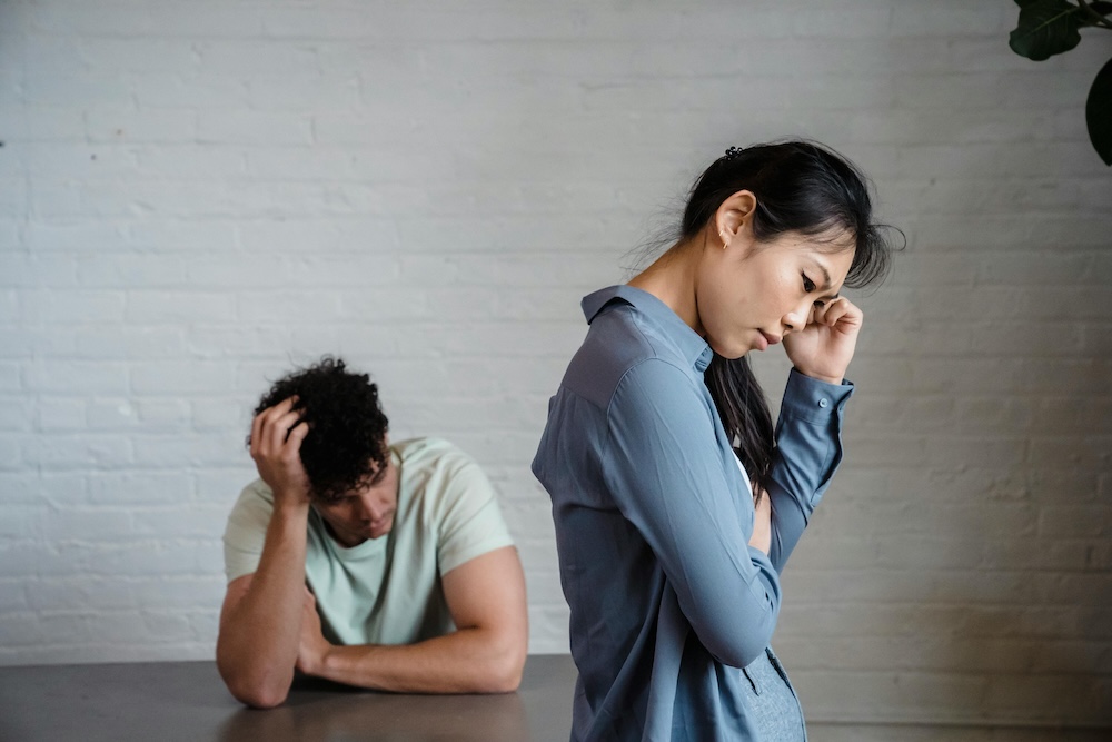A woman looks distressed and helpless as her partner emotionally shuts down, an example of the 'stonewalling' from Gottman's Four Horsemen, a communication breakdown that often requires couples therapy to resolve.