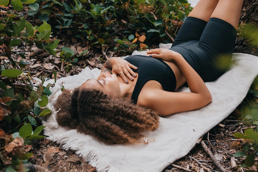 Woman demonstrating the box breathing technique for anxiety relief with hands placed on her chest and stomach for breath awareness.