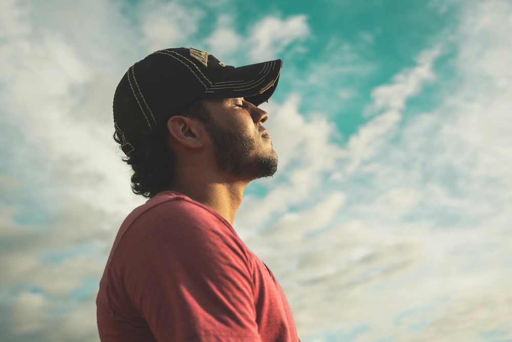A man taking a mindful breath with his eyes momentarily closed, representing the 'urge surfing' and 'bouncing eyes' techniques.