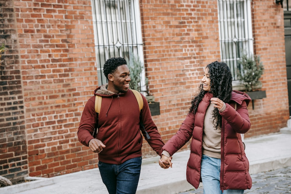 A Black couple smiling and holding hands in a nature-inspired setting, symbolizing the goal of rebuilding secure, healthy attachments.