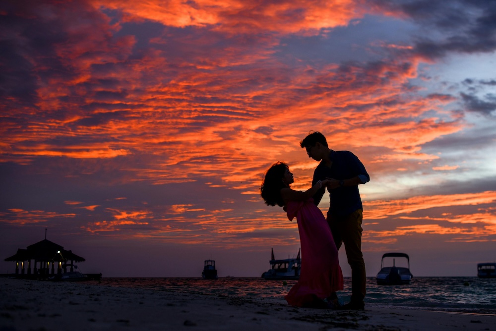 A happy couple sharing an intense, joyful moment on a beach, representing the initial love-bombing stage of a trauma bond.