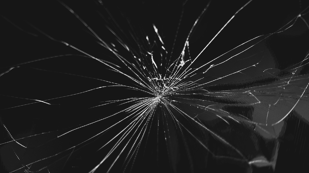 Close up of shattered glass shards, illustrating how a trauma trigger can suddenly break a person's sense of present-moment safety.