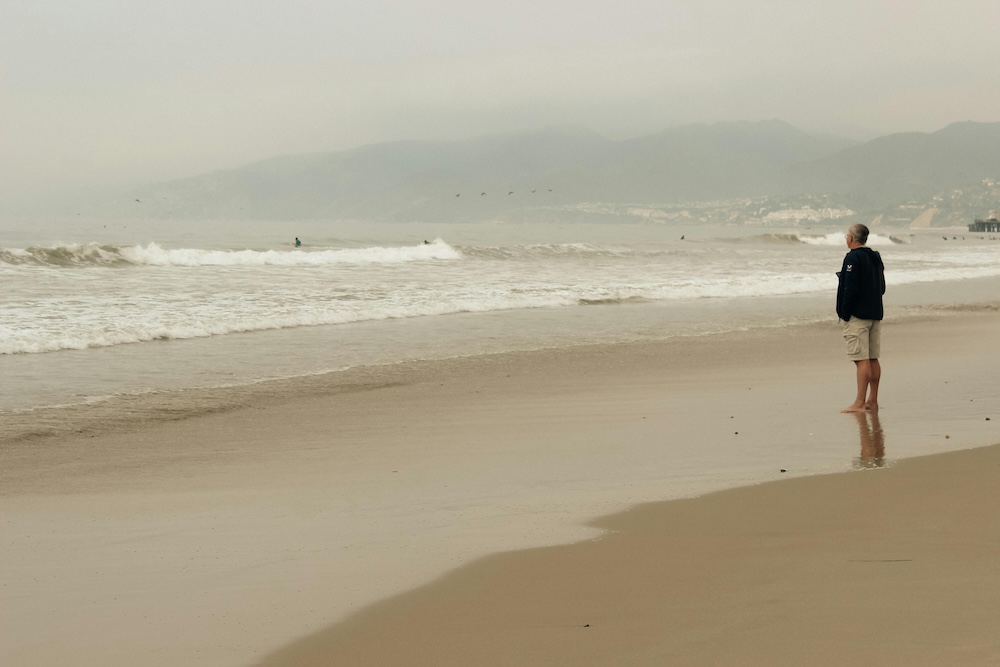 A person walking on a serene beach, evoking a sense of calm and balance essential for the stabilization process in therapy.