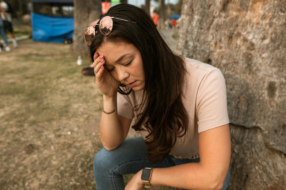 A close-up of a person with their hand on their forehead, illustrating the physiological stress and amygdala hijack caused by relational betrayal.