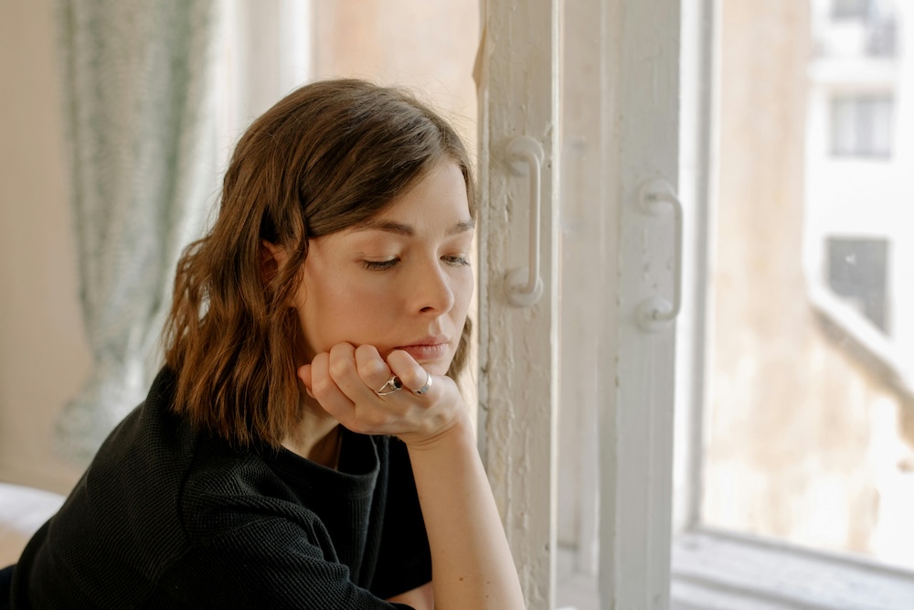 A close-up, reflective shot of a partner looking out a window, capturing the primary emotions of fear and loneliness hidden beneath surface-level anger.
