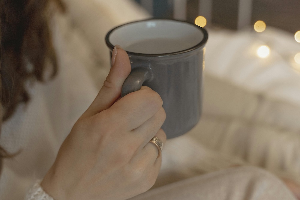 A person holding a warm cup of tea in a calm setting, symbolizing the essential first stage of trauma recovery: creating physical and emotional safety.