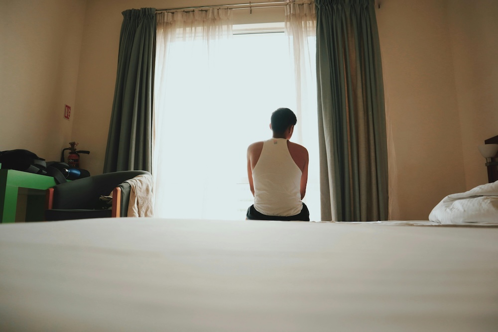 A person sitting contemplatively by a window, representing the internal work and reflection required during the sexual sobriety phase.