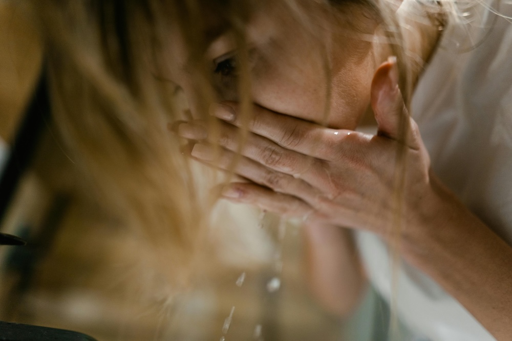 woman splashing cold water on face to reset polyvagal system