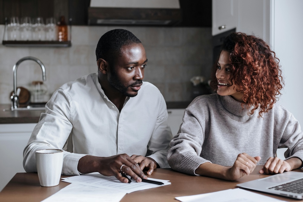 A diverse couple engaged in a deep, focused conversation in a home kitchen, showing empathy through body language.