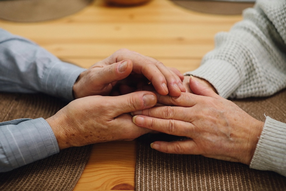 Close-up of a couple holding hands during a supportive conversation, representing healing through professional counseling.