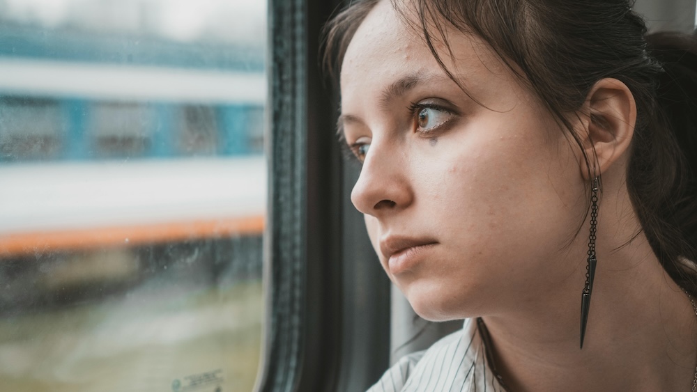 partner processing a porn addiction relapse -- woman by window in thought