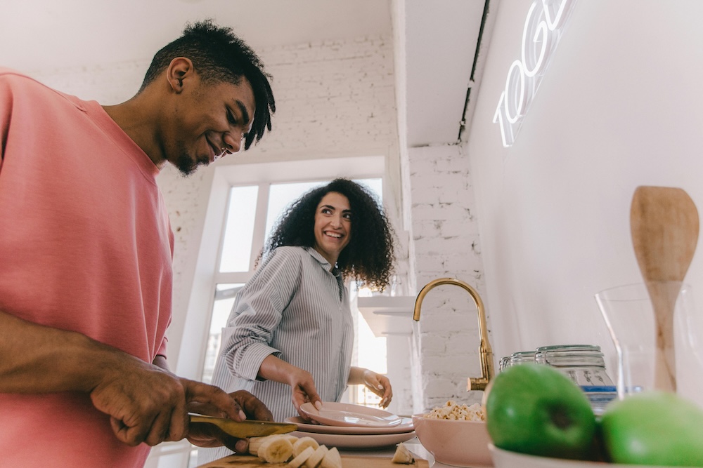 A happy, diverse couple sharing kitchen responsibilities, demonstrating an equitable partnership in marriage.