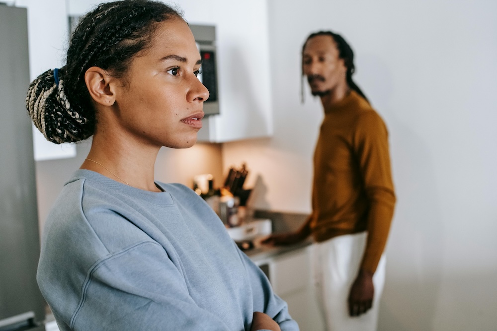 A stable, high-functioning couple sharing a kitchen space logistically but lacking eye contact or emotional engagement.