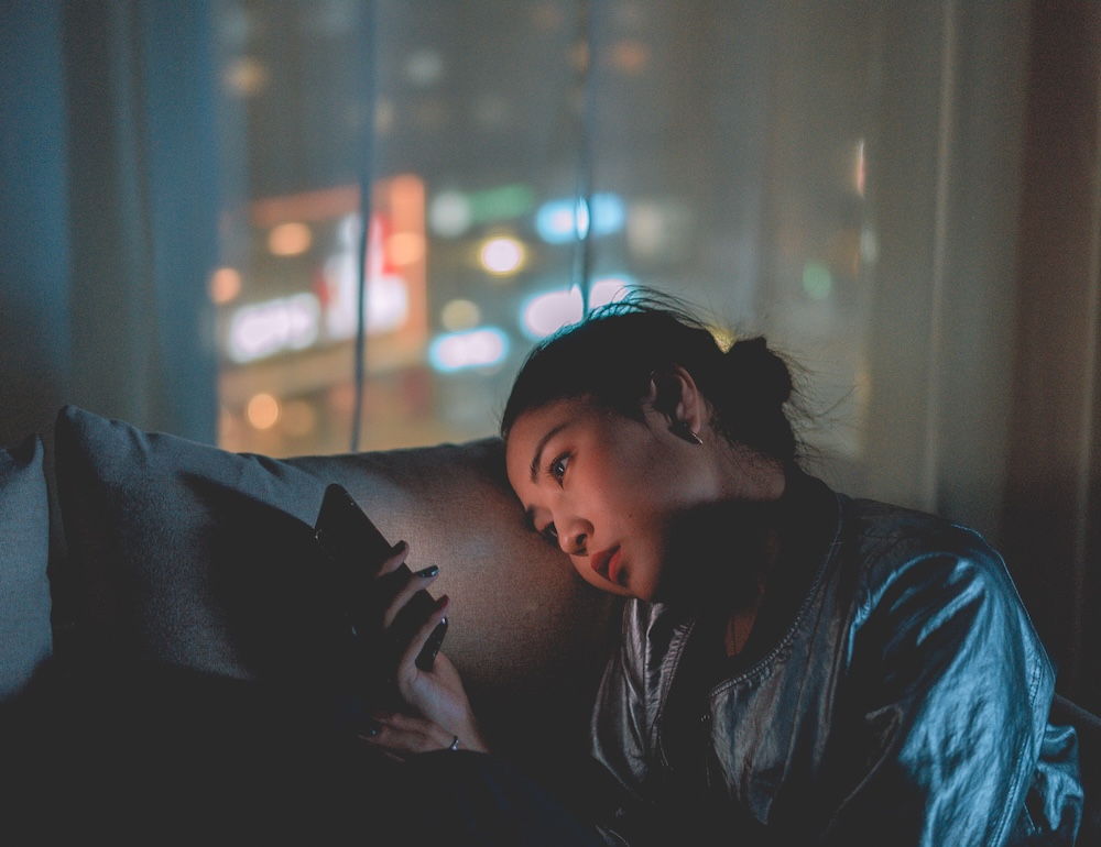 Person looking at phone screen in quiet contemplation, rereading old messages after discovering betrayal