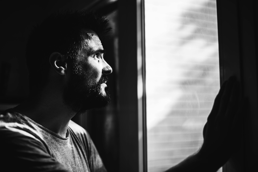 Person alone at a window in the morning, introspective — the deeper work for the betrayer is healing the wounds that drove the behavior