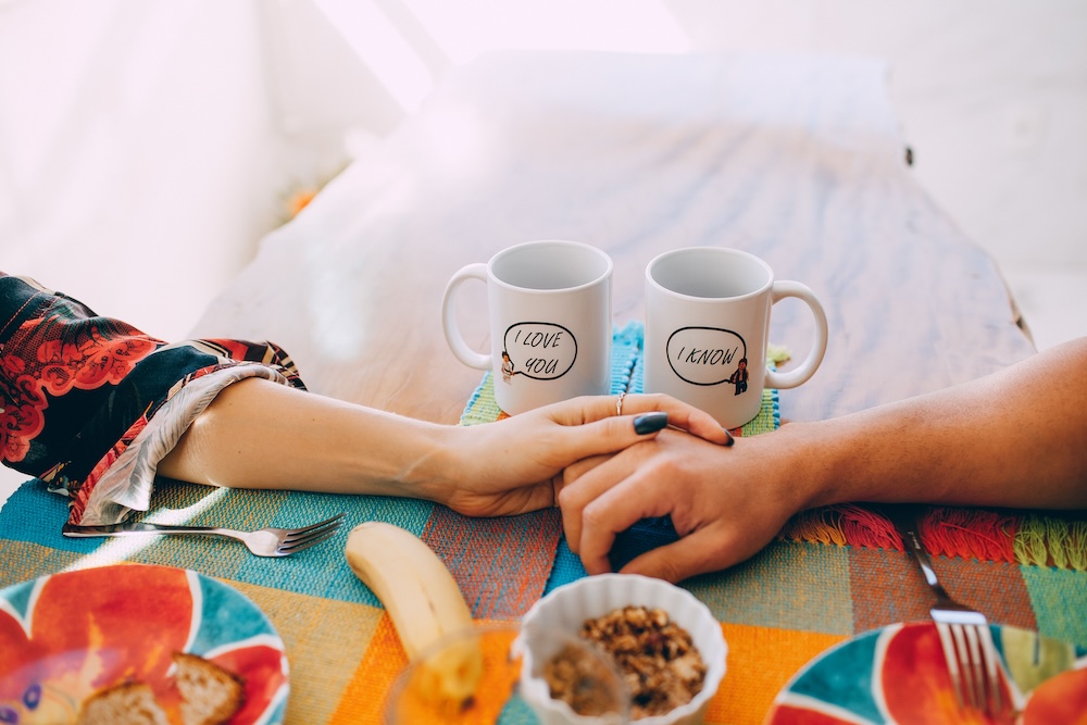 Porn induced erectile dysfunction recovery — a couple's hands joined across a kitchen table in soft morning light.