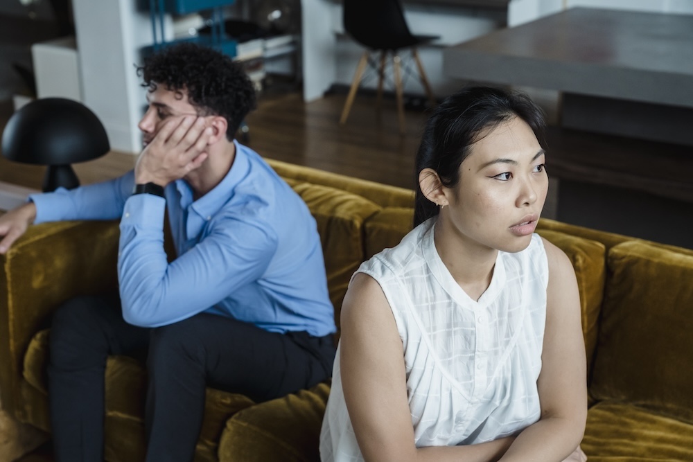 how the unfaithful partner can heal. A couple sitting apart in quiet evening light, the moment when the betrayer's shame begins to dominate the room