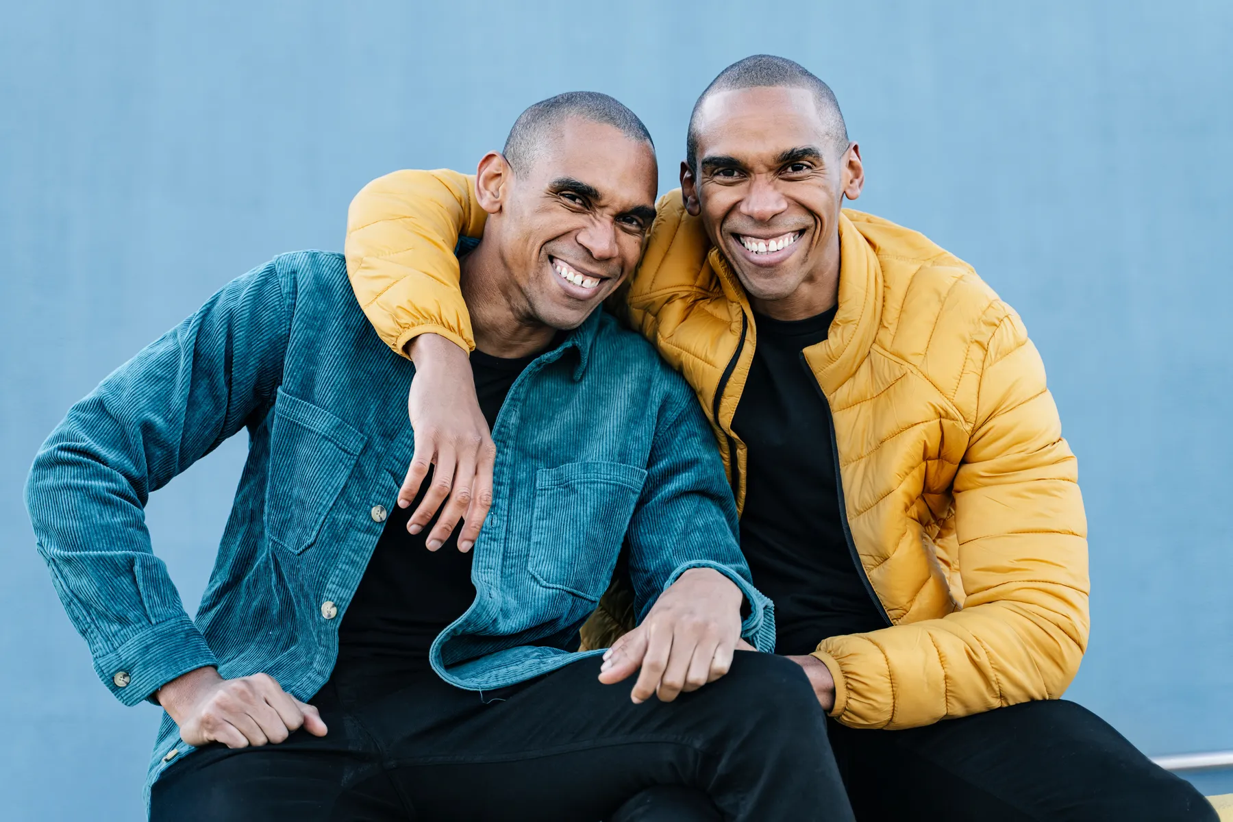 Identical twin brothers sitting side by side in different jackets, alike on the surface and different underneath
