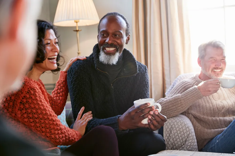 A group of friends laughing together over coffee, the kind of real connection recovery rebuilds.