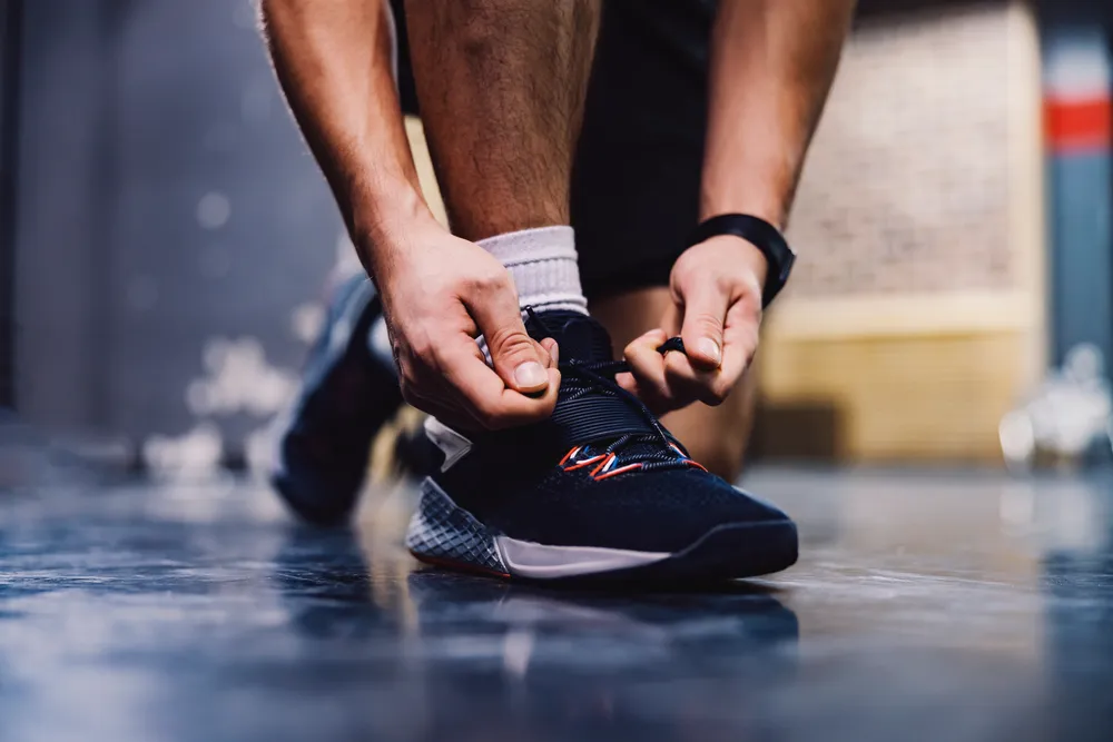 Close-up of hands tying running shoes, the small repetitions that retrain the brain's reward system