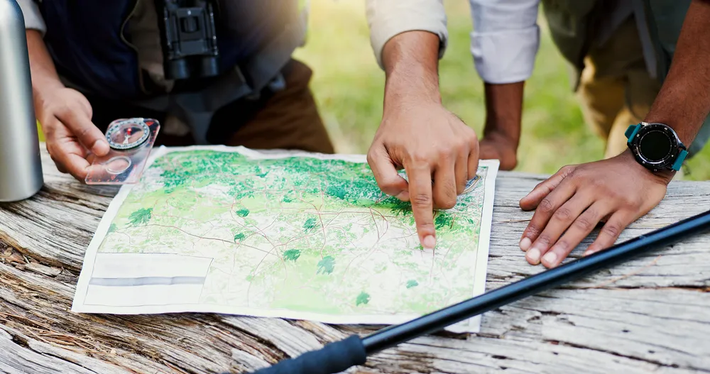 Hands studying a creased trail map in morning light, treating a relapse as data rather than a verdict