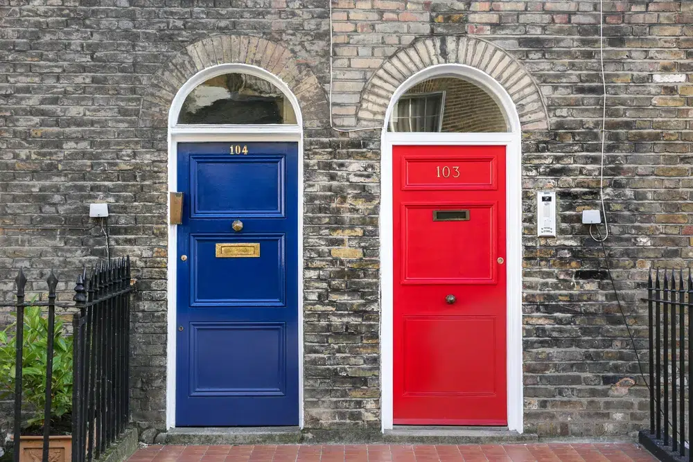 Two different colored front doors side by side in a brick wall, two possible futures after betrayal