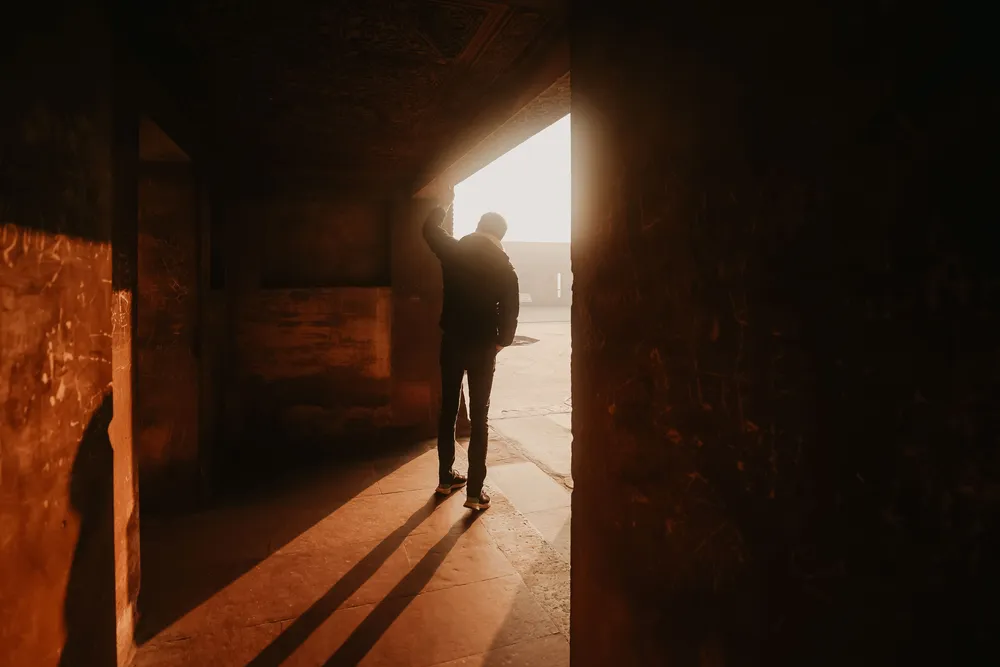 A person stepping out a doorway into daylight, illustrating the start of individual trauma treatment after betrayal