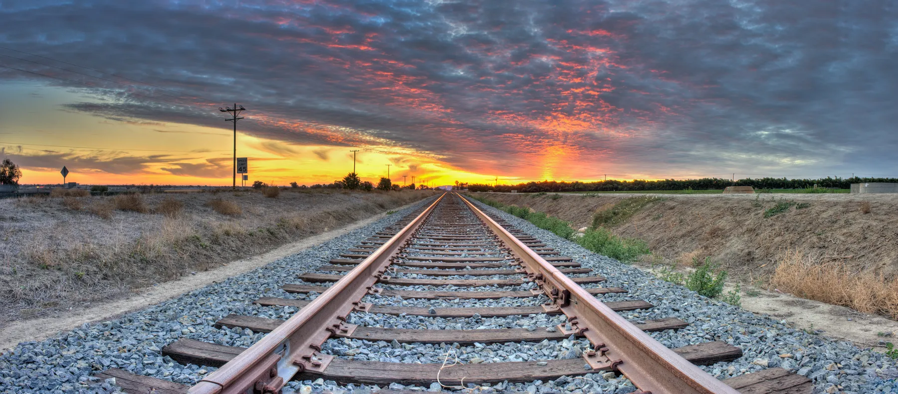 Railway tracks running side by side toward a sunset horizon, an image of feeling lonely in a relationship.