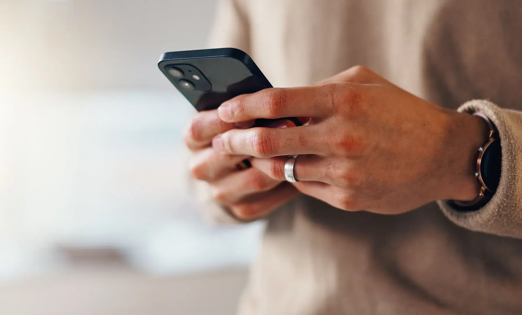 Close-up of hands texting on a smartphone, like the message threads partners find when asking if paying for OnlyFans is cheating