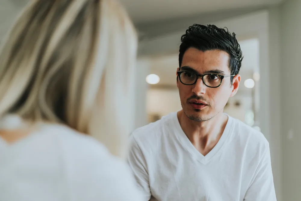 Two people in a serious face-to-face conversation at home, one listening closely